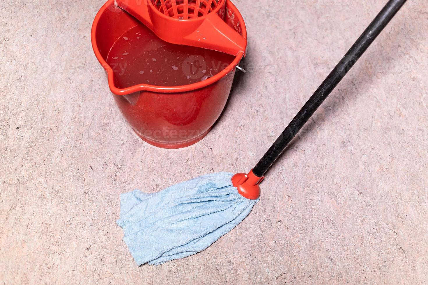 mop cleans linoleum flooring near red bucket photo