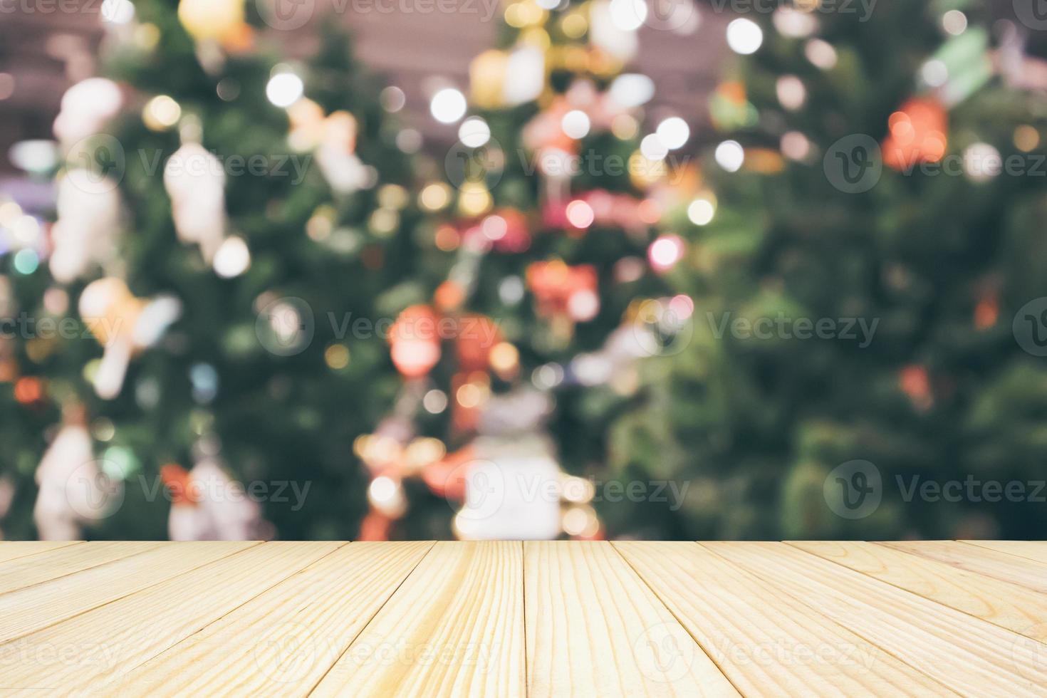 mesa de madera con luz de bokeh festiva de vacaciones de navidad abstracta en el fondo borroso del árbol para exhibición de productos de montaje foto