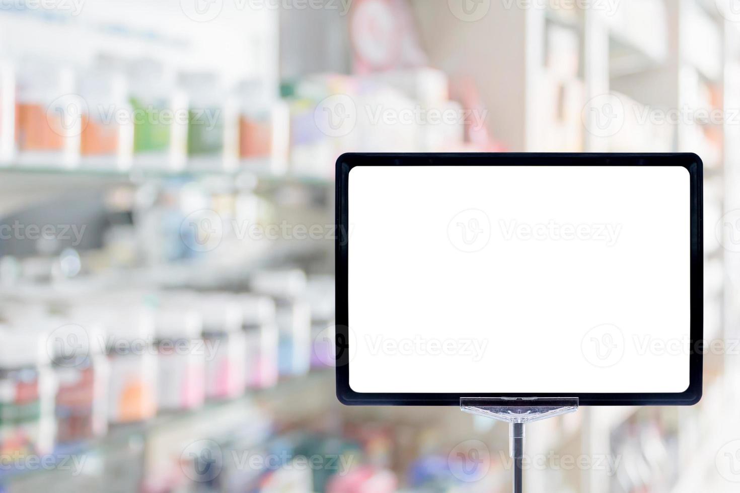 Muestra de tablero de precio en blanco en la farmacia fondo borroso con medicamentos en los estantes foto