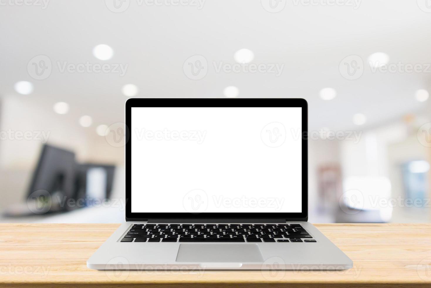 Laptop with blank screen on desk table with blur office interior background photo