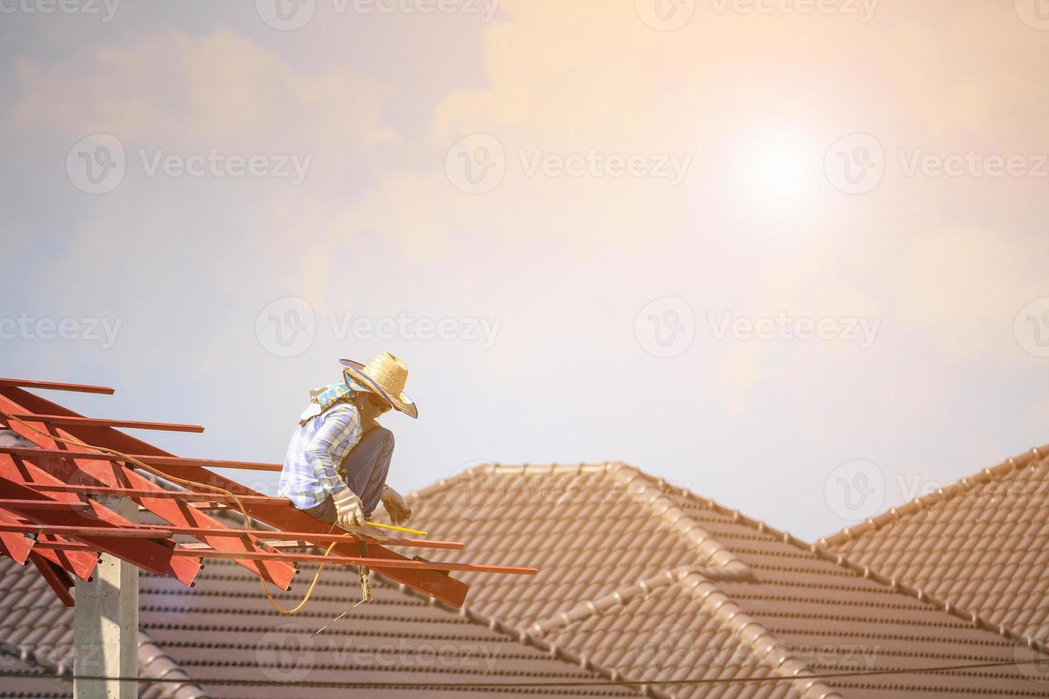 welder workers installing steel frame structure of the house roof at building construction site photo