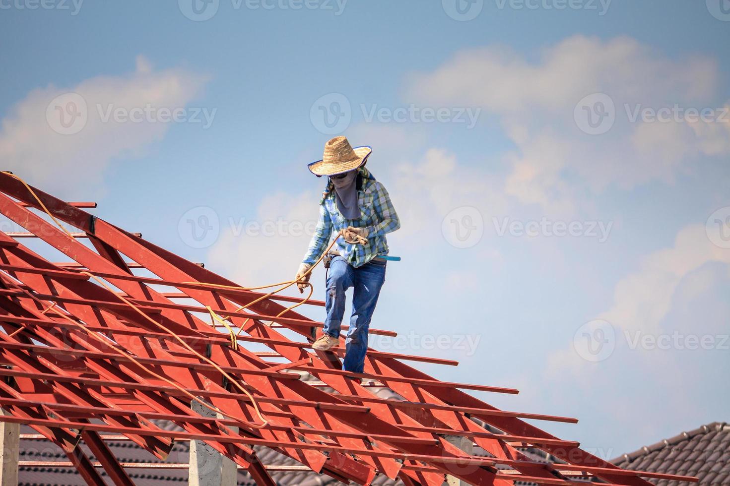 welder workers installing steel frame structure of the house roof at building construction site photo