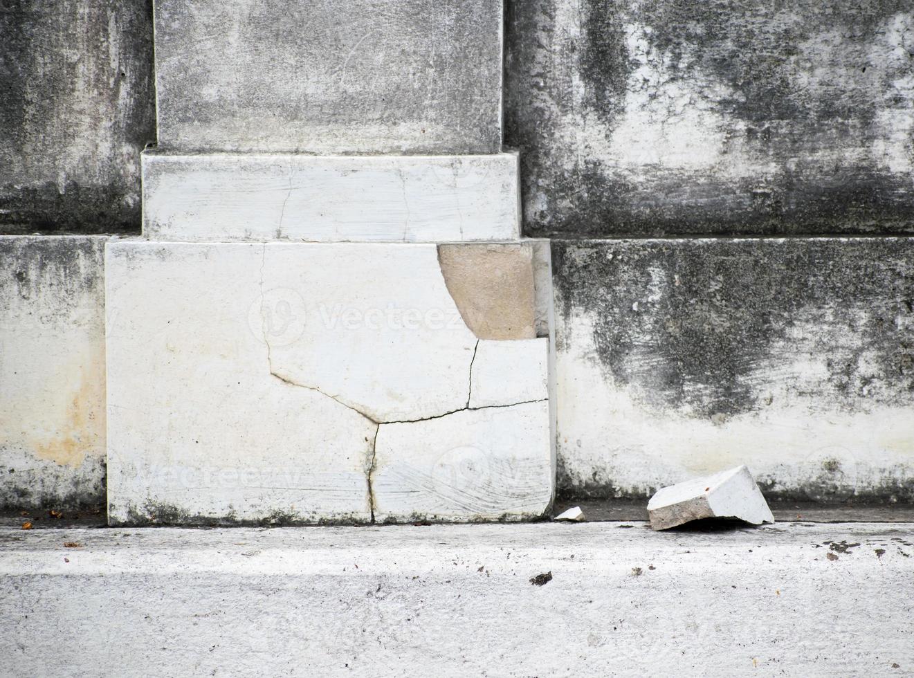 Cracked concrete pillar fragments are falling nearby, surface as background. photo