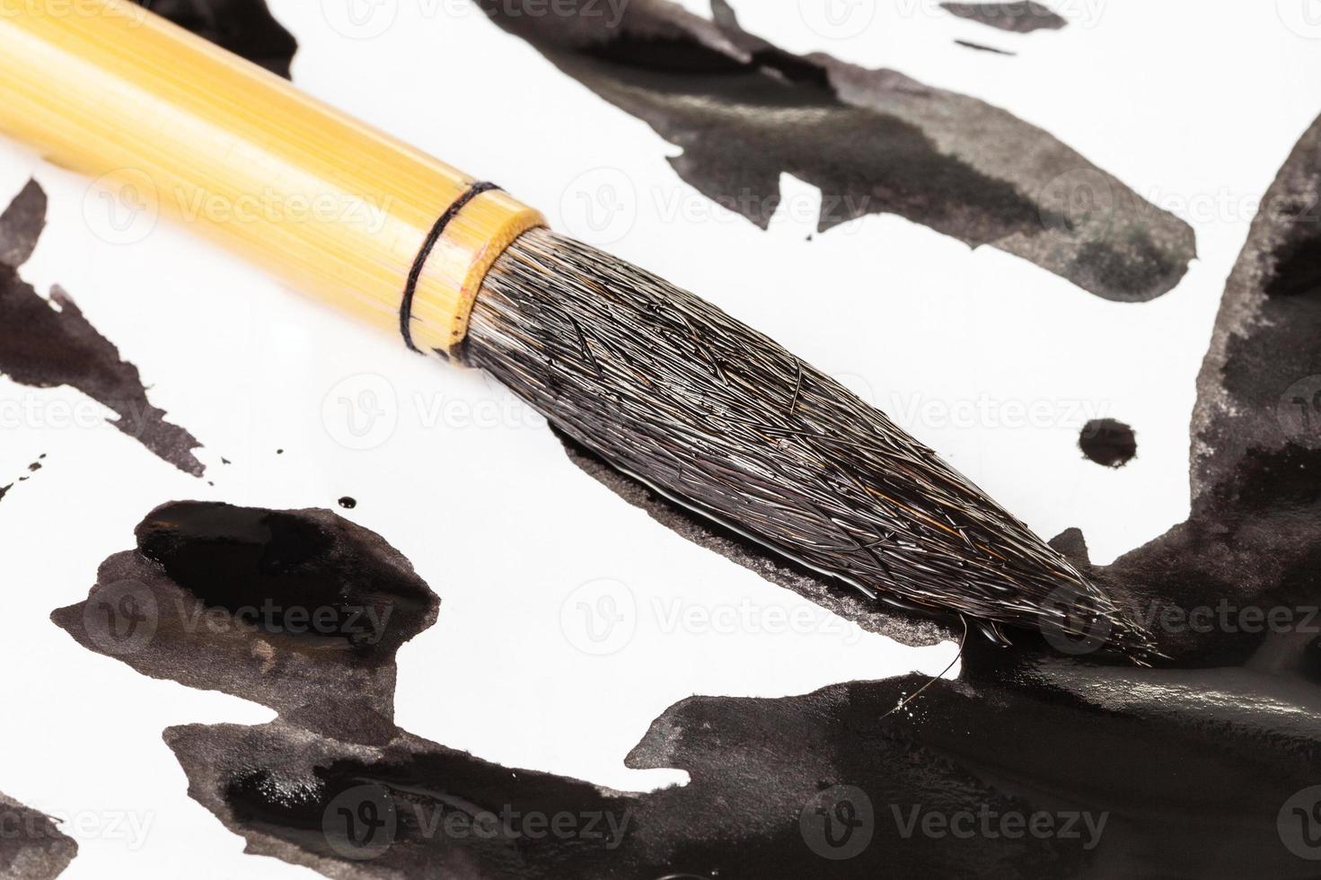 black tip of paintbrush over ink spots close up photo