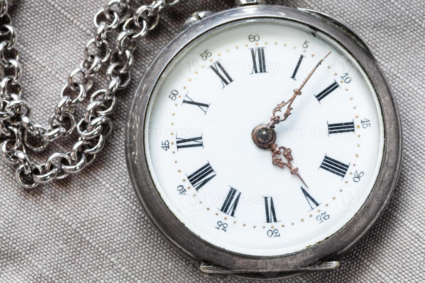 shabby silver pocket watch on gray textile photo