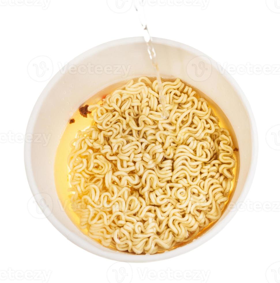 pouring hot water into cup with instant noodles photo