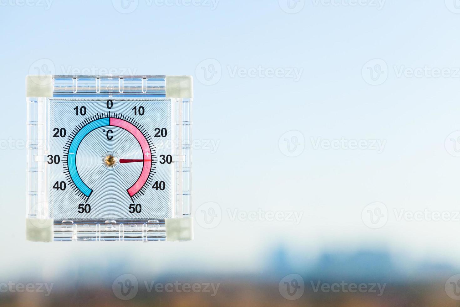 thermometer on home window and blurred skyline photo