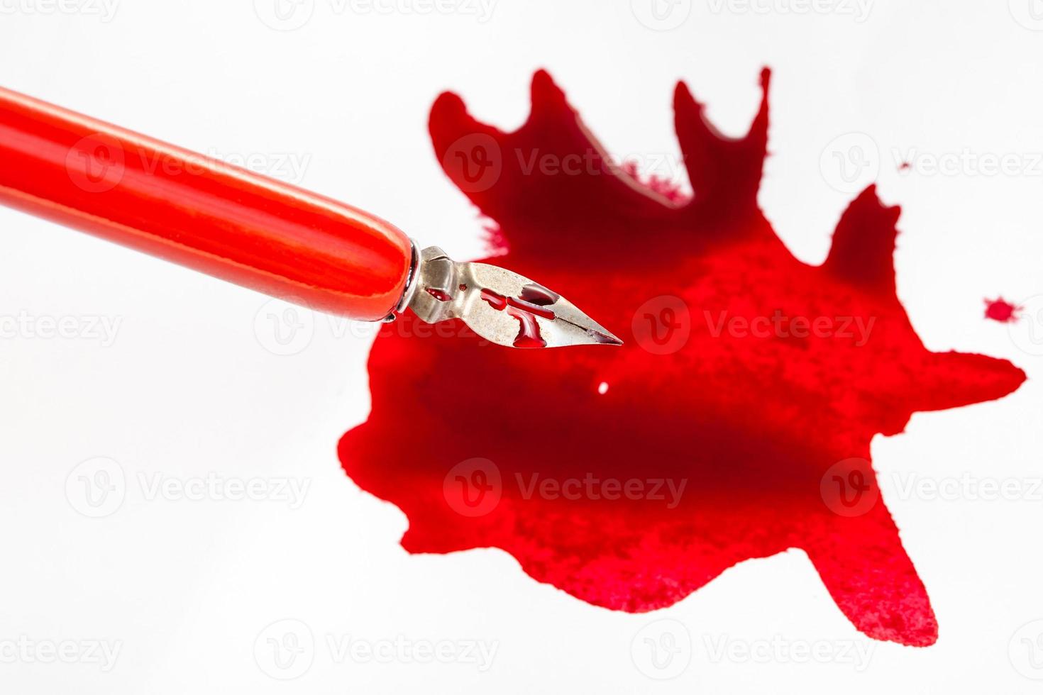 above view of nib in red dip pen over red ink blot photo