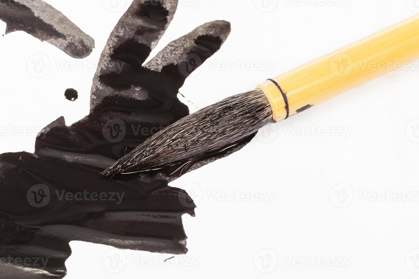 black colored tip of paintbrush over ink stains photo