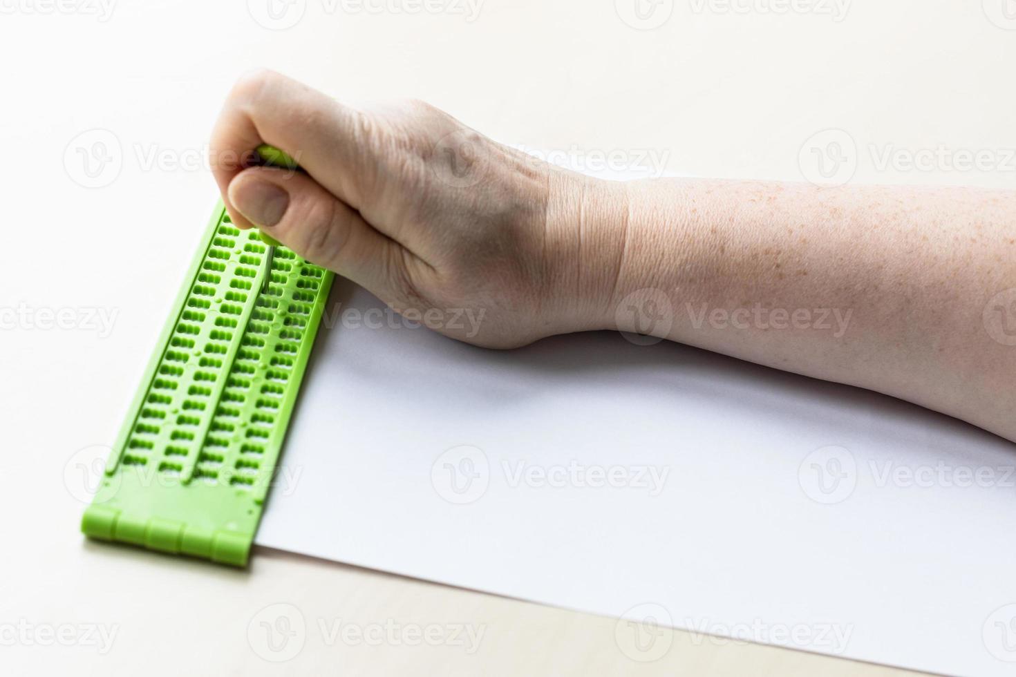 hand writes words in braille with slate and stylus photo