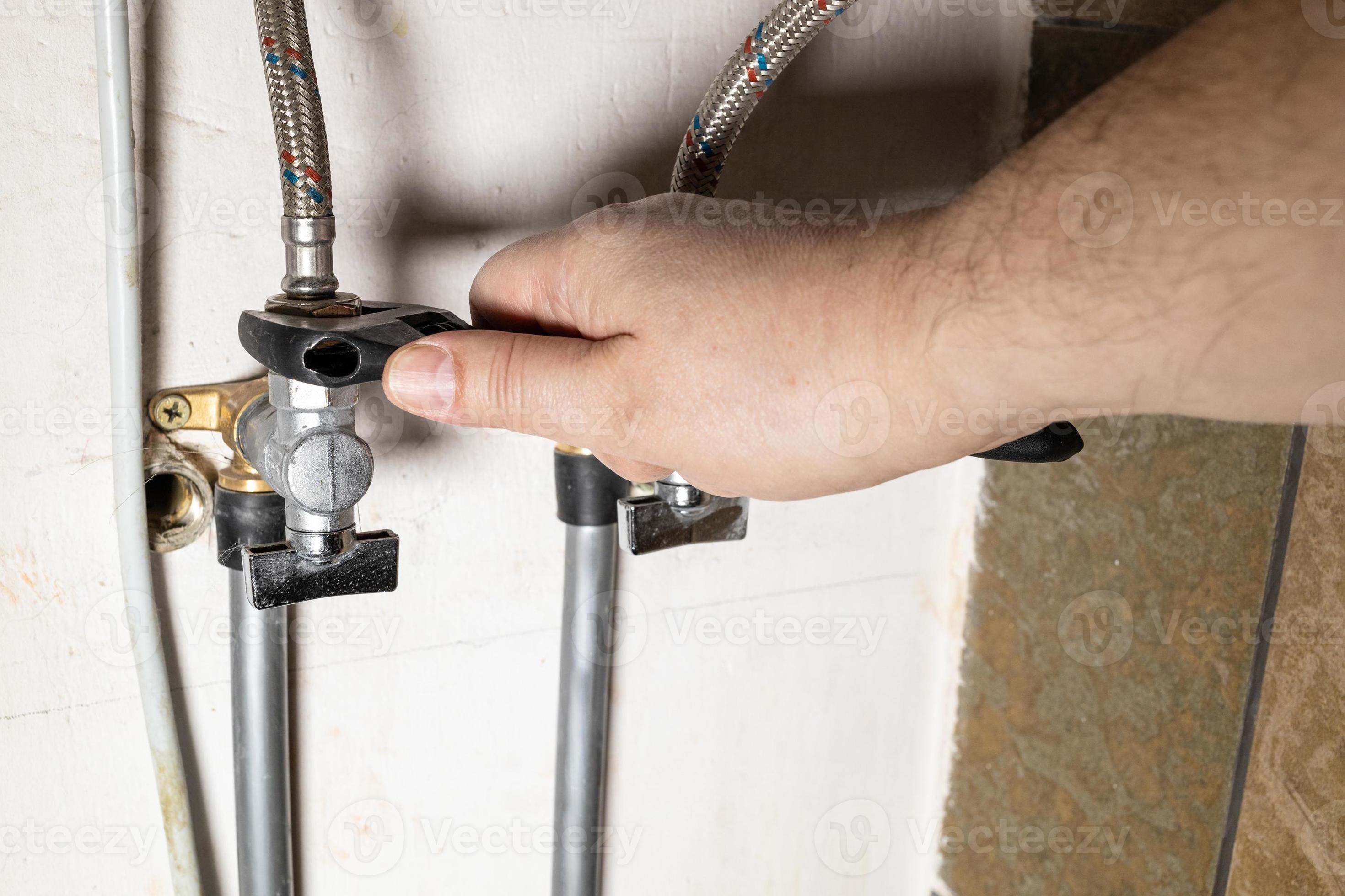 hand installs water stop tap by adjustable wrench 11184889 Stock Photo