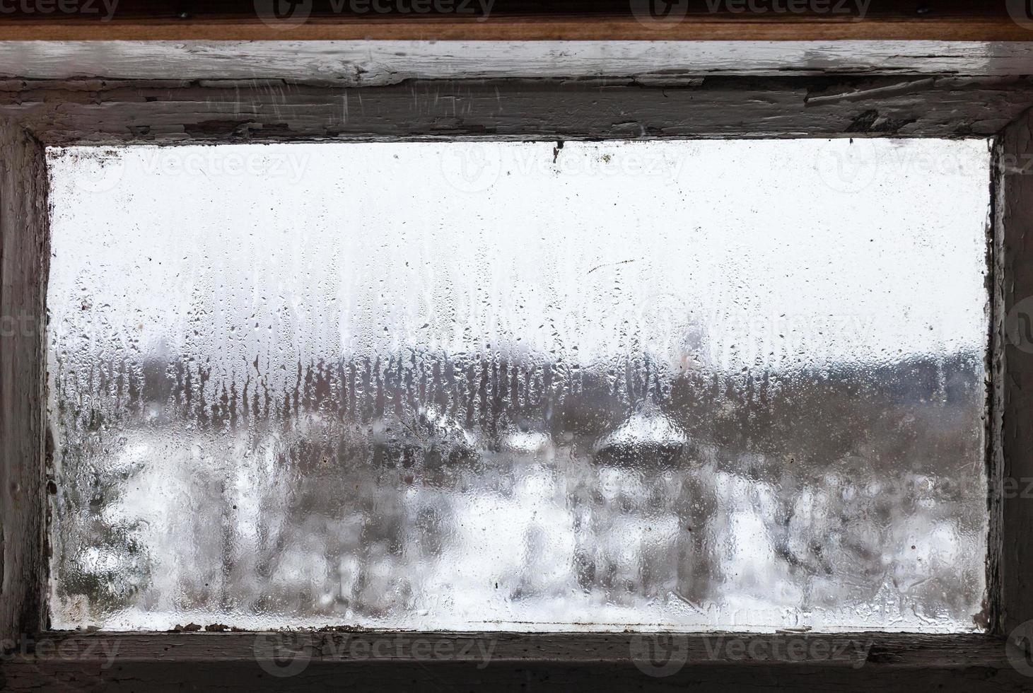water drops from melting ice on frozen window photo