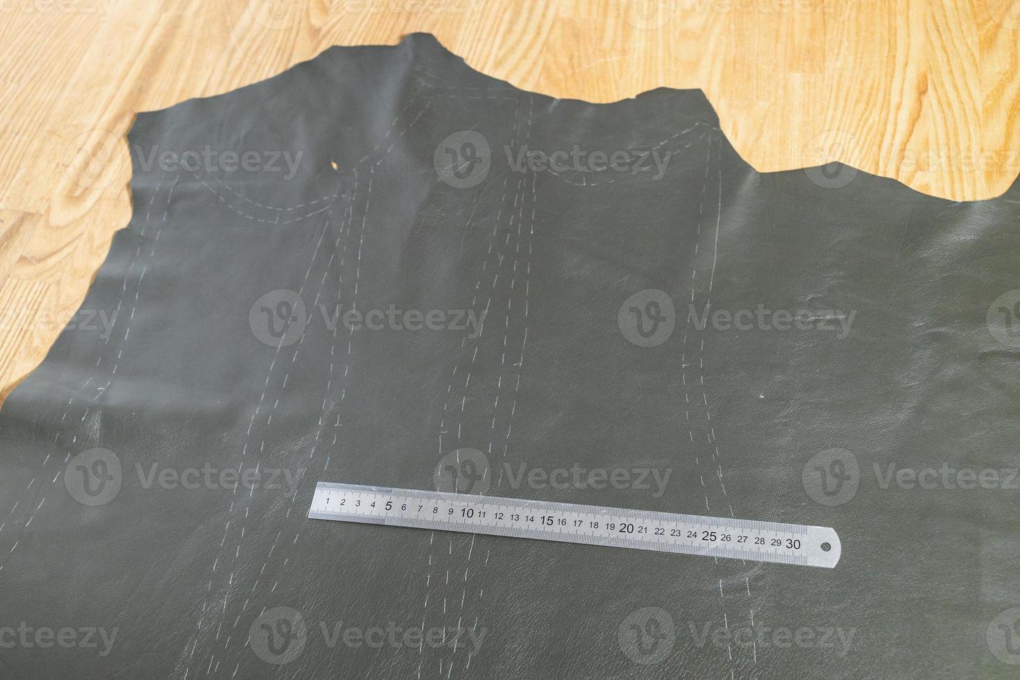 steel ruler on leather with drawn pattern at table photo