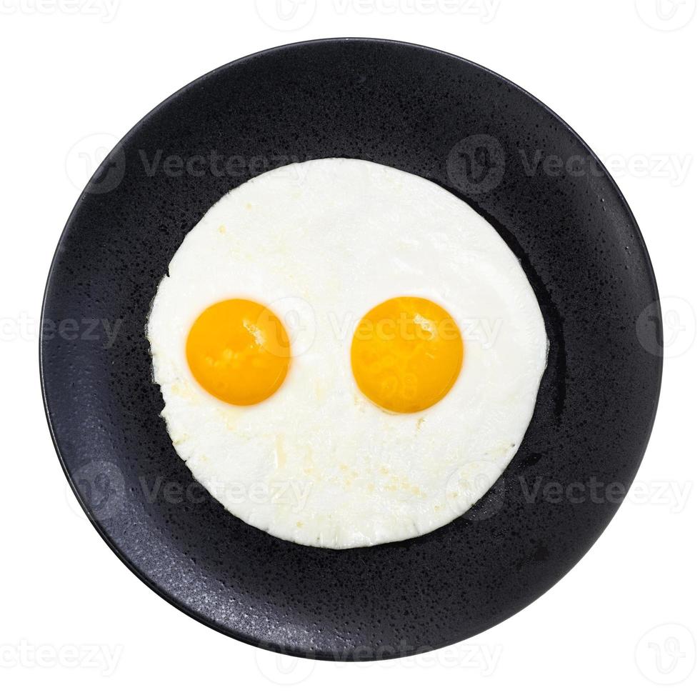 top view of fried eggs on black plate isolated photo