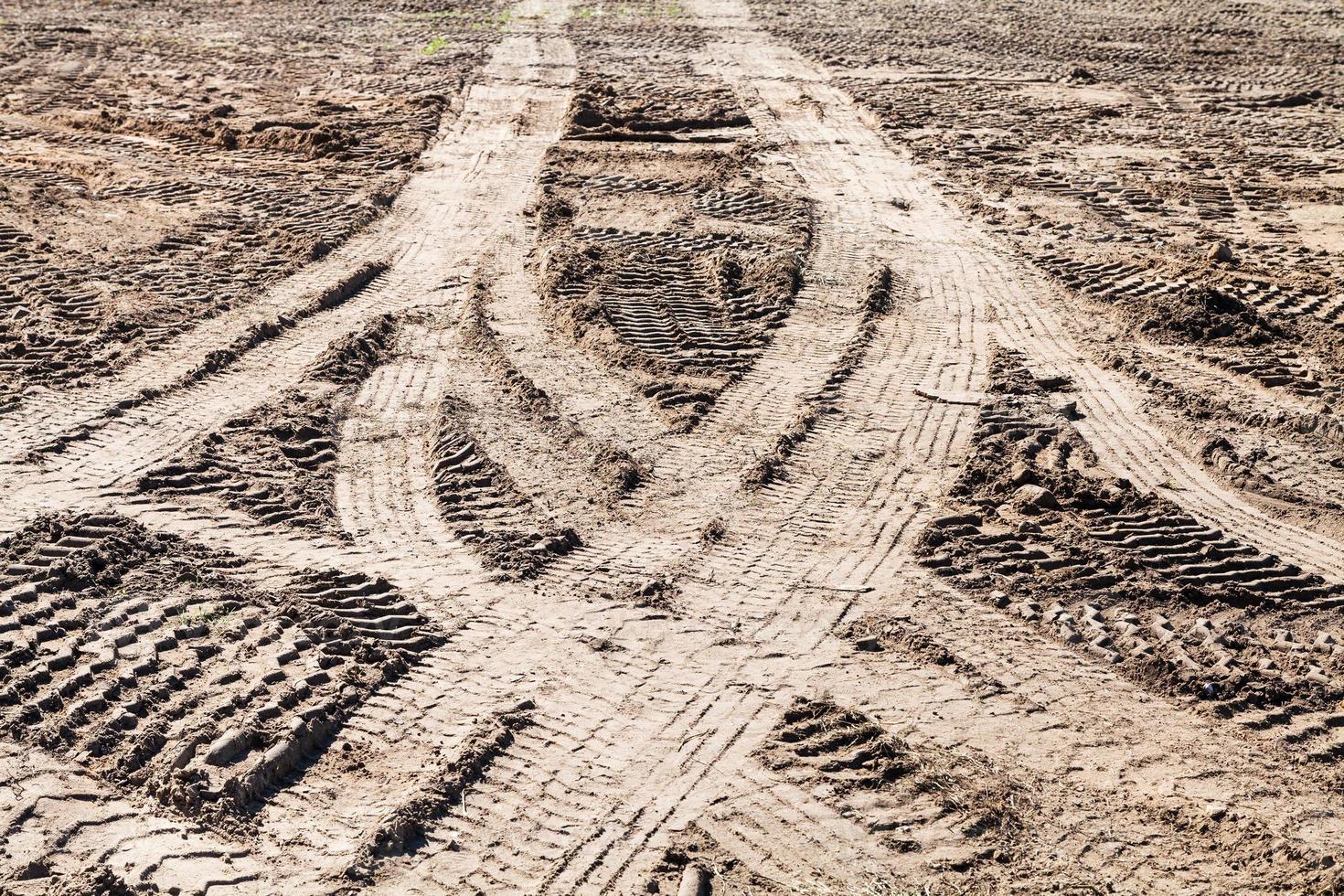 symmetrical traces of car tires on dirty field photo