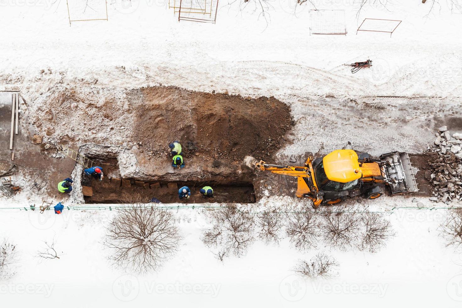 above view of road workers changing pipe in winter photo
