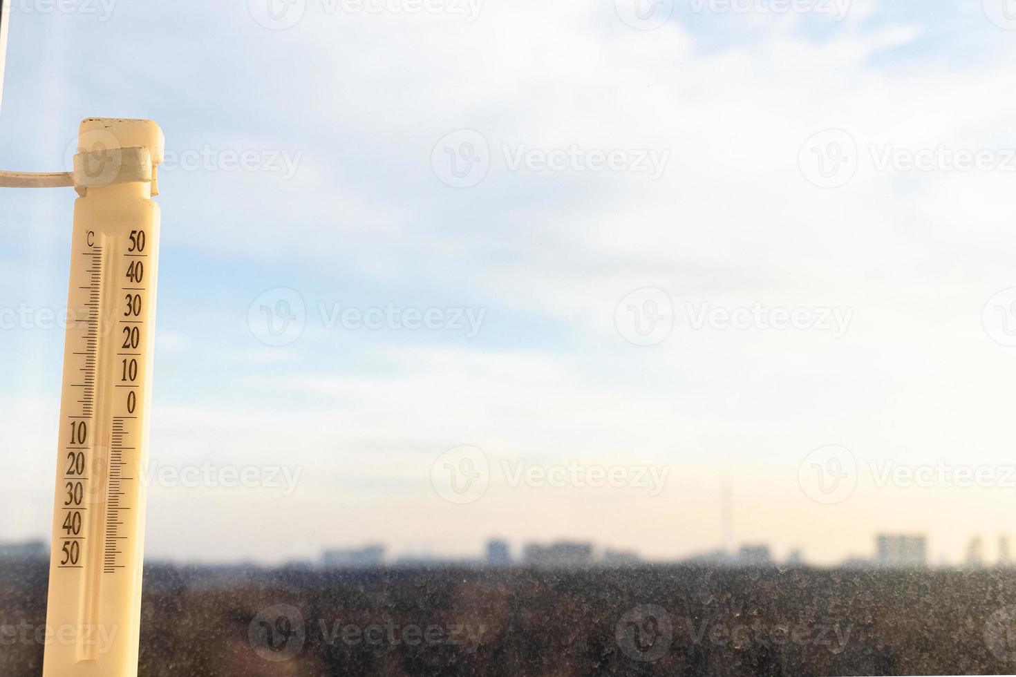 outdoor thermometer on window lit by sunrise sun photo