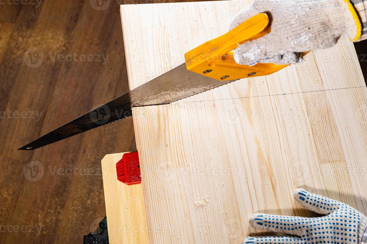 above view of sawing wooden board with hand saw photo