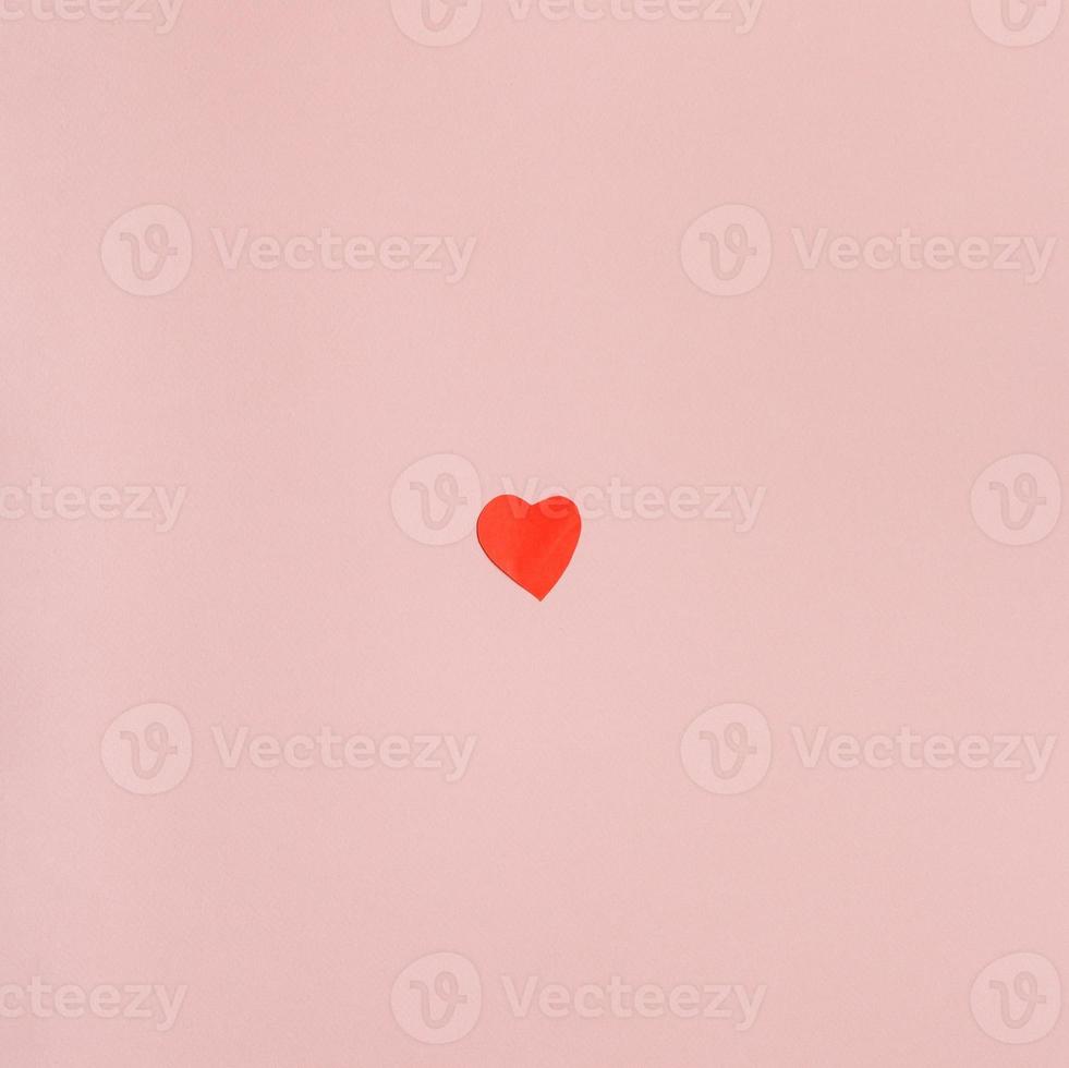 corazón cortado en papel rojo sobre papel rosa claro foto