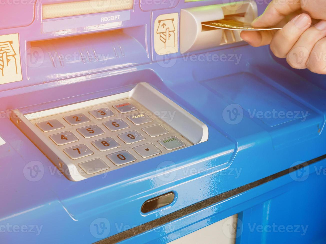 female hand inserting ATM card into ATM bank machine photo