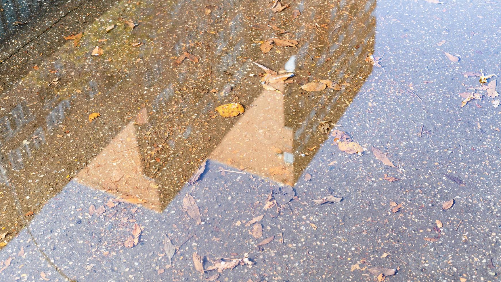 puddle with fallen leaves and reflection of house photo