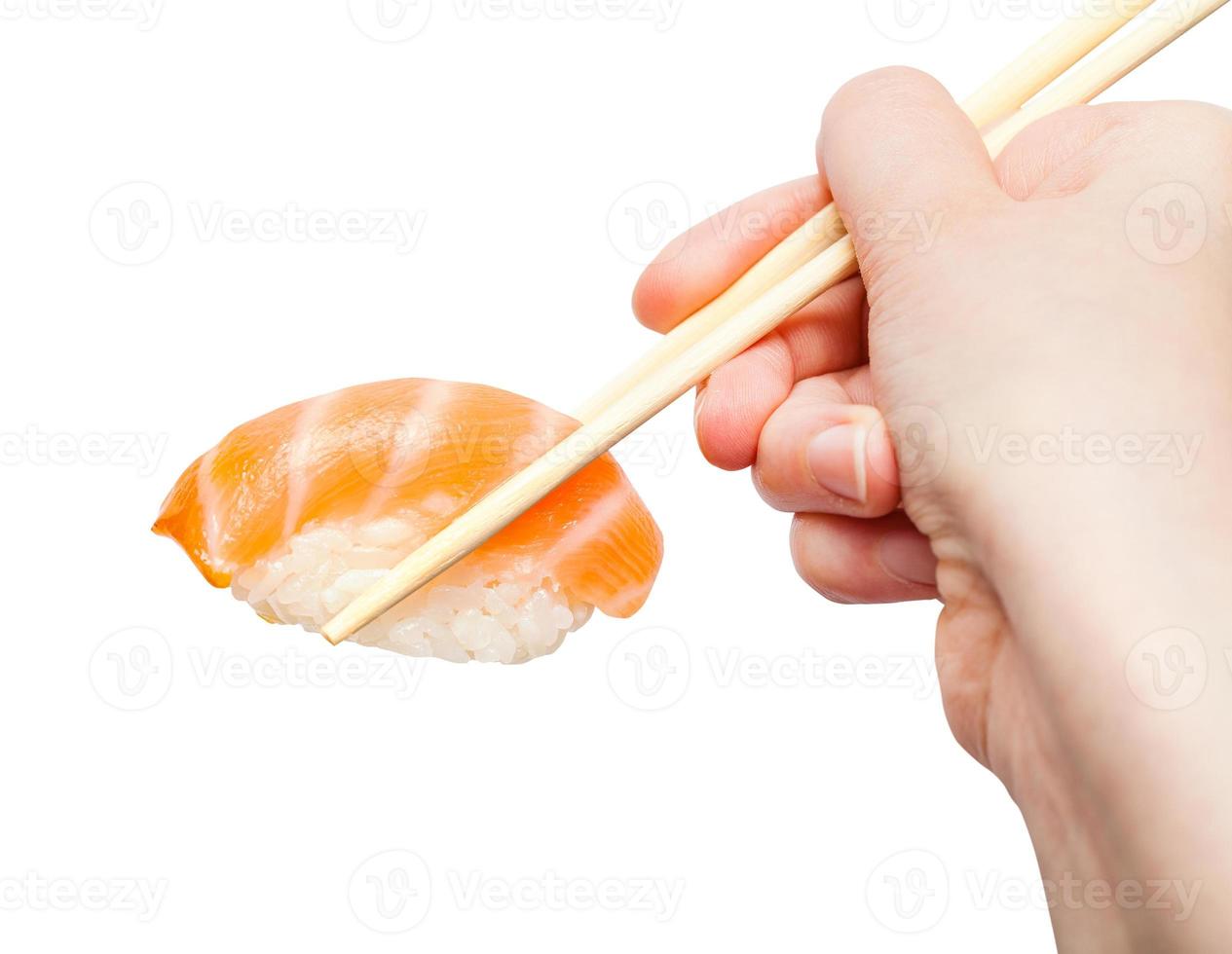 chopsticks hold nigiri sushi with salmon close up photo