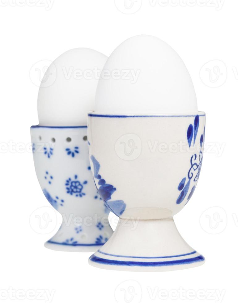 side view of two white boiled eggs in egg cups photo