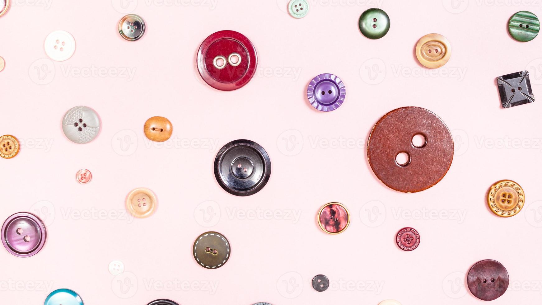 top view of various buttons arranged on pink photo