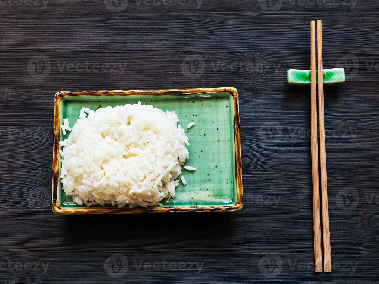 boiled rice on green plate and wooden chopsticks photo