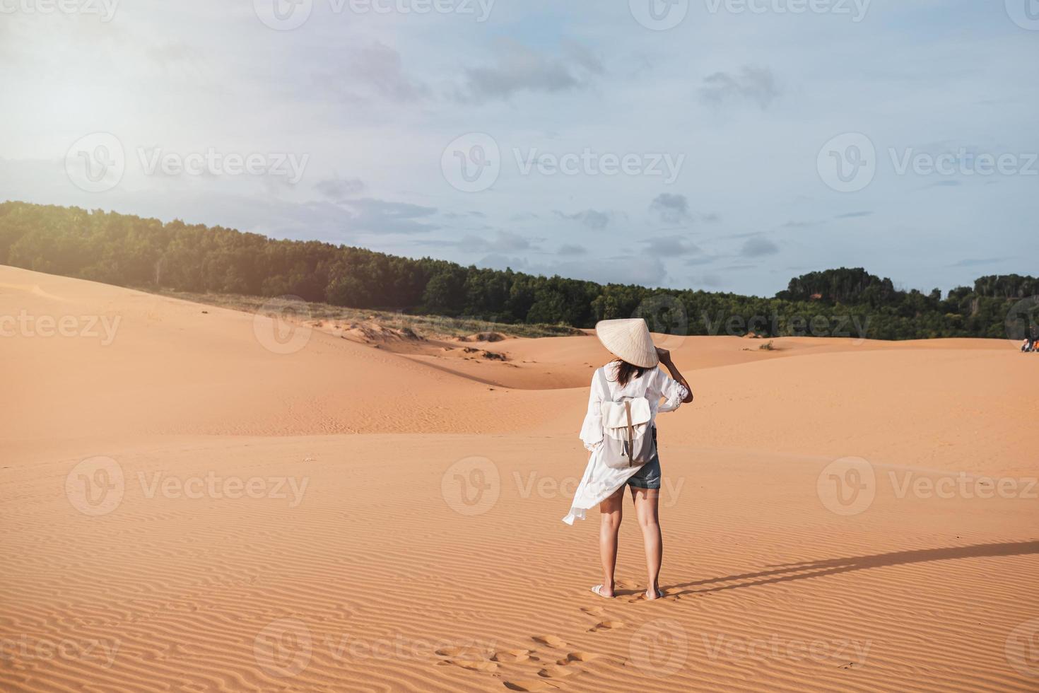 mujer joven viajera caminando en dunas de arena roja en vietnam, concepto de estilo de vida de viaje foto