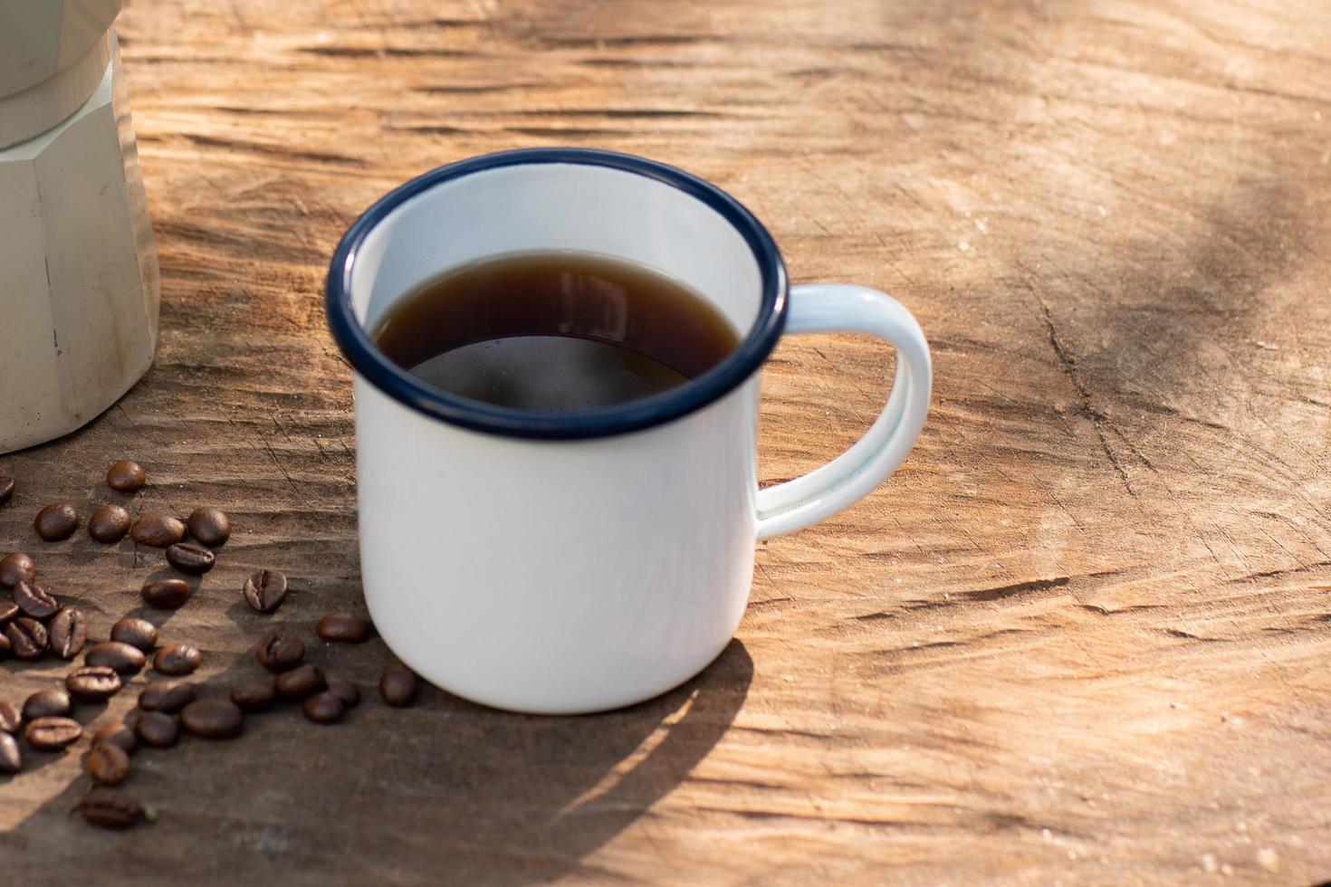 white enamel coffee mug on the old wooden table photo