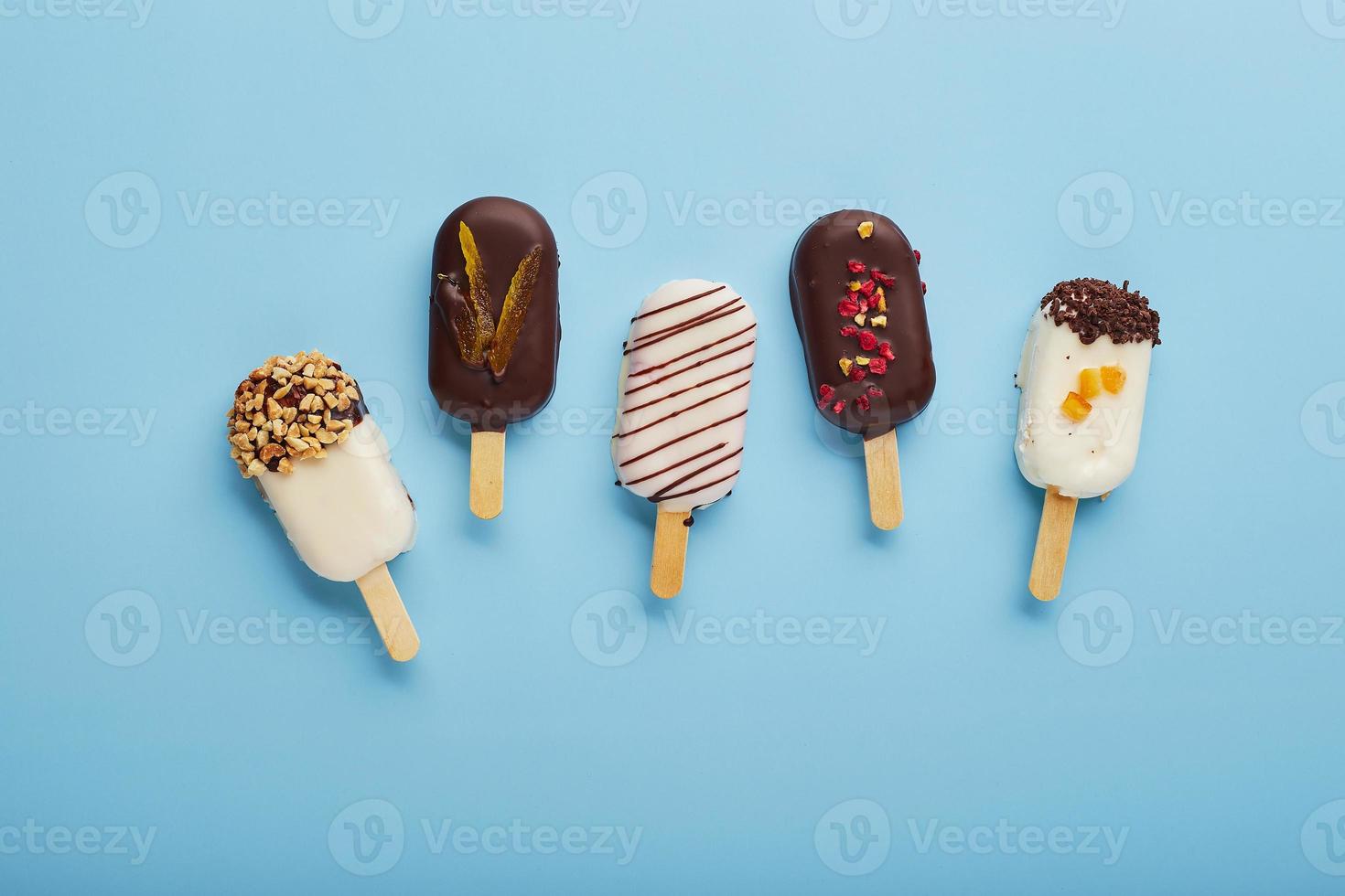 Mousse dessert with fruit flavors in the form of popsicle ice cream on blue background. photo