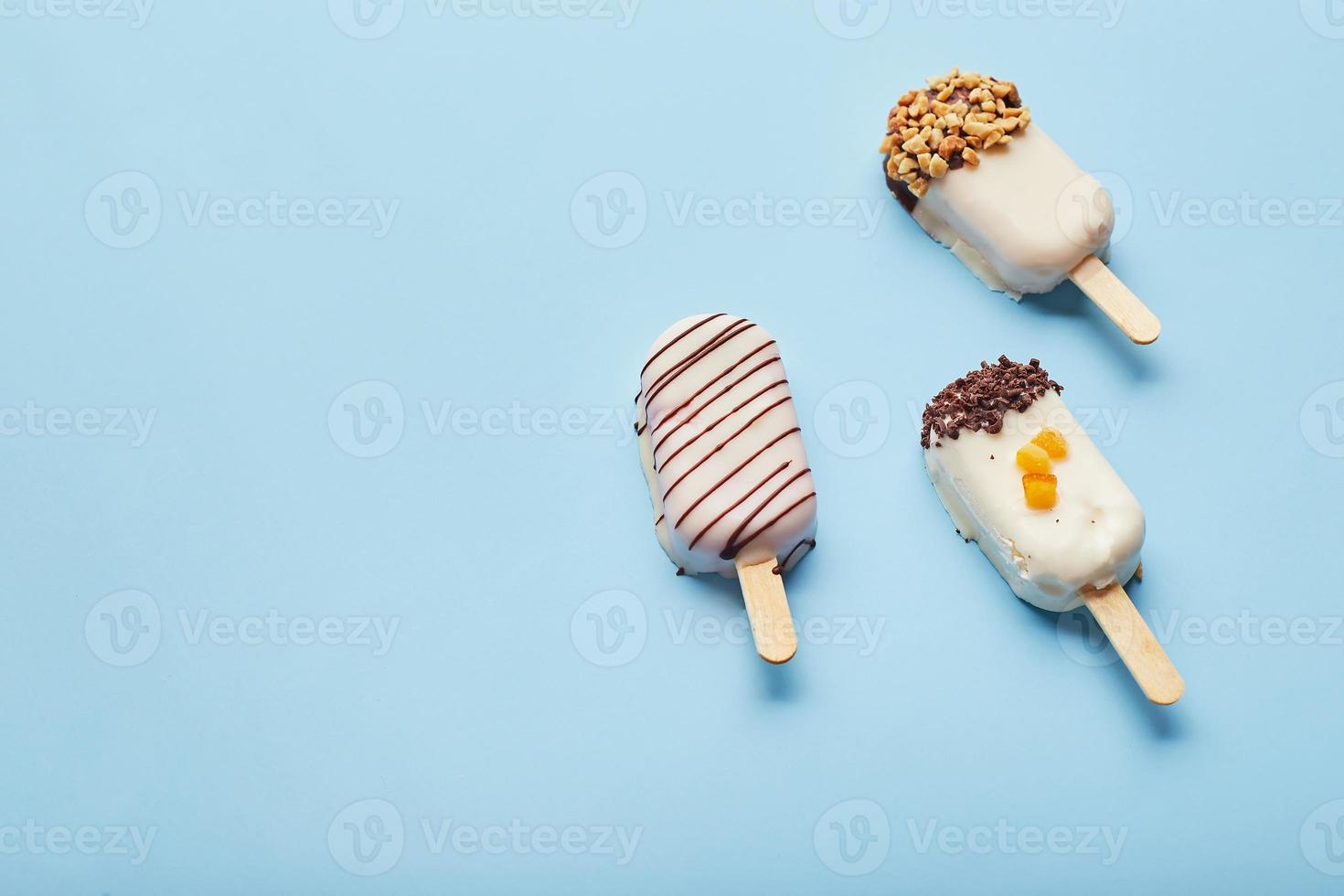 postre de mousse con sabores de frutas en forma de helado de paleta sobre fondo azul. foto