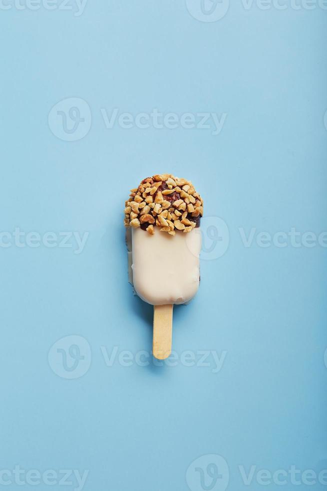 postre de mousse con sabores de frutas en forma de helado de paleta sobre fondo azul. foto