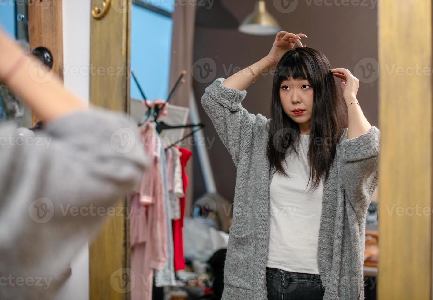 chica asiática coreana elige ropa, se cuida divertida frente al espejo en la sala de estar. 11193499 Foto de stock en Vecteezy