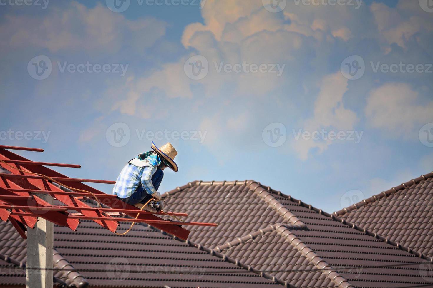 welder workers installing steel frame structure of the house roof at building construction site photo