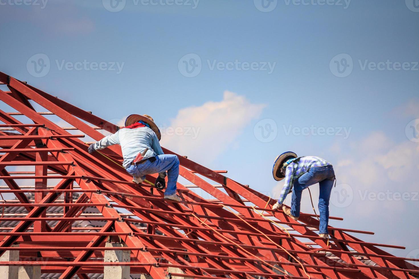 welder workers installing steel frame structure of the house roof at building construction site photo