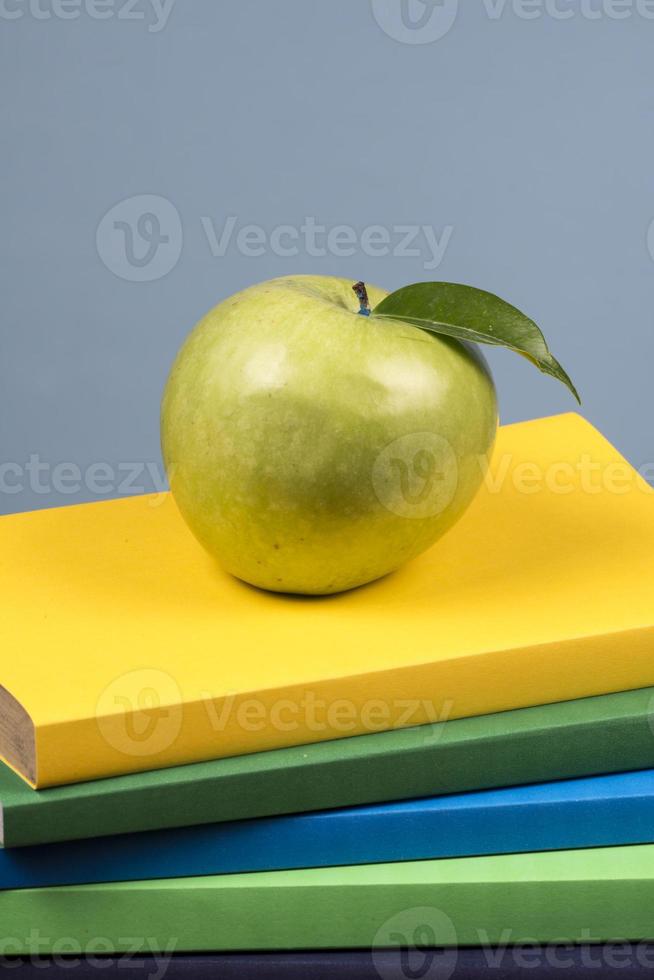 fruta de manzana encima de una pila de libros, en la parte posterior de las clases escolares. foto