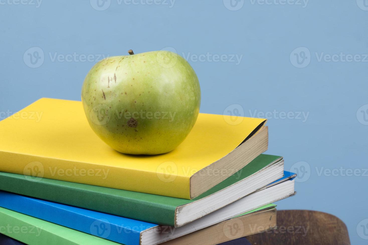 Apple fruit on top of a book stack, on the back of school classes. photo