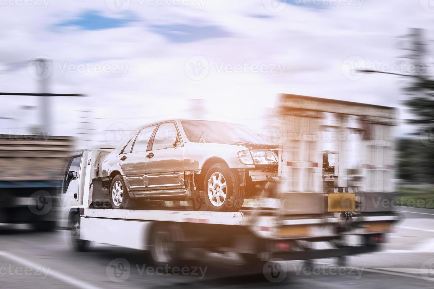 Broken car on tow truck after traffic accident, on the road service photo