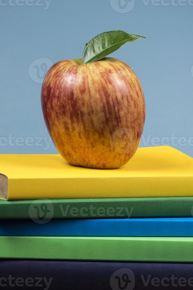 fruta de manzana encima de una pila de libros, en la parte posterior de las clases escolares. foto