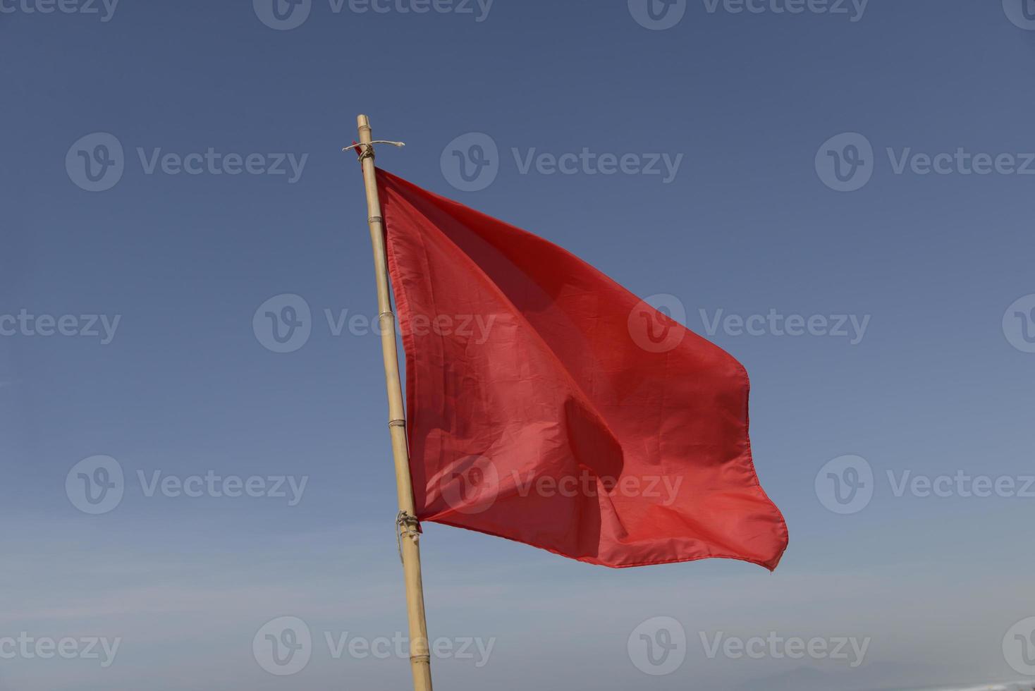 bandera roja meciéndose en el viento sobre un fondo de cielo azul foto