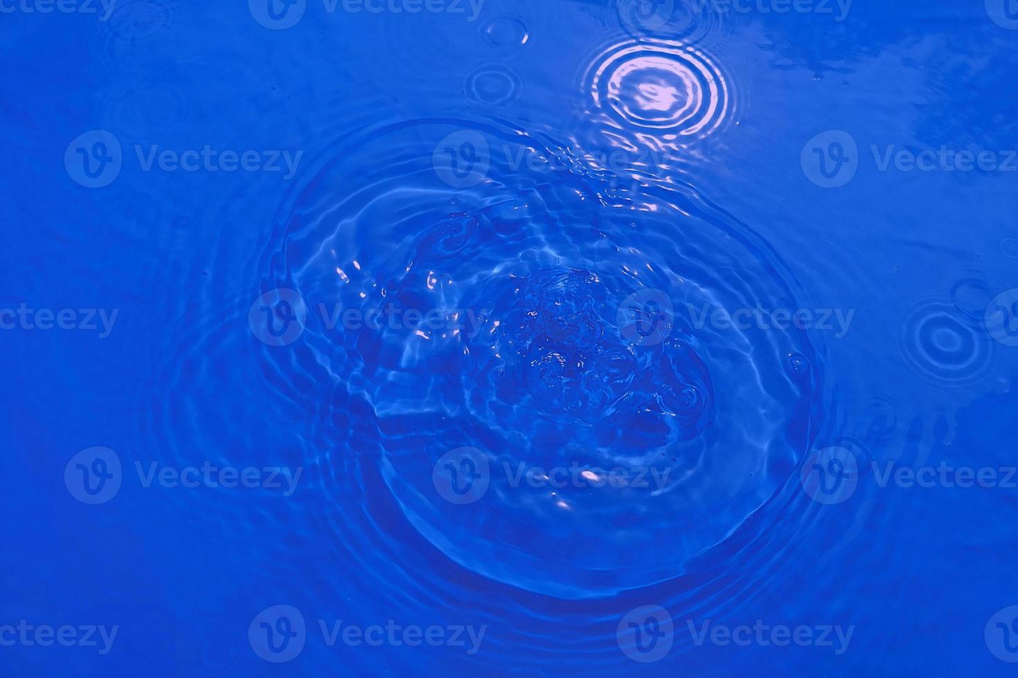 Defocus blurred transparent blue colored clear calm water surface texture with splashes and bubble. Trendy abstract nature background. Water wave in sunlight with copy space. Blue watercolor shining. photo