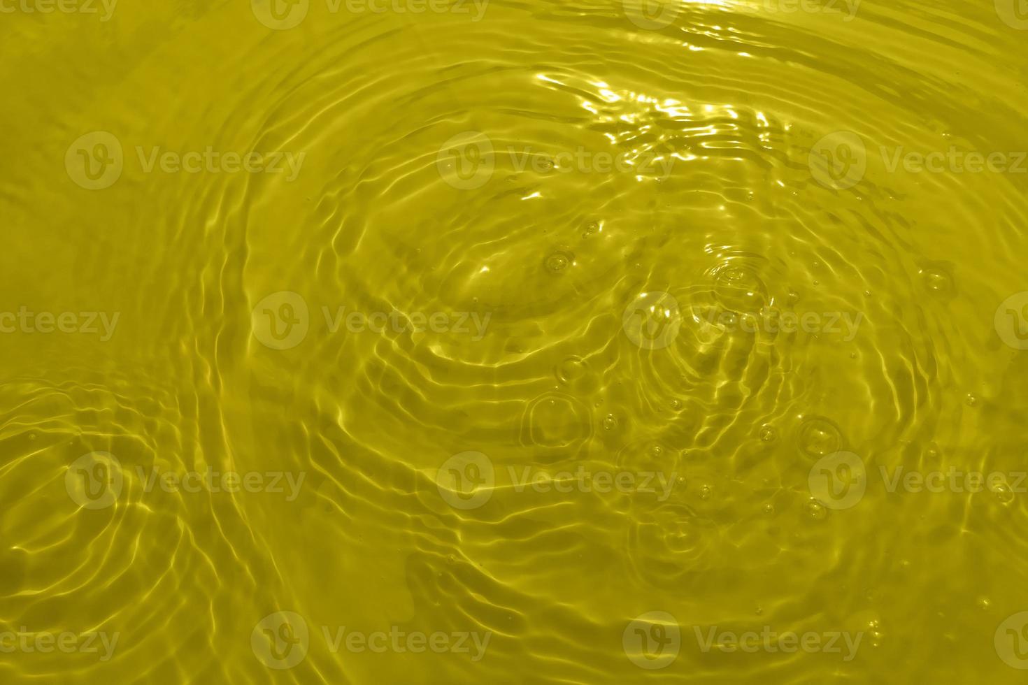 Defocus blurred transparent yellow colored clear water surface texture with splashes and bubble. Trendy abstract nature background. Water wave in sunlight with copy space. Yellow watercolor shining. photo
