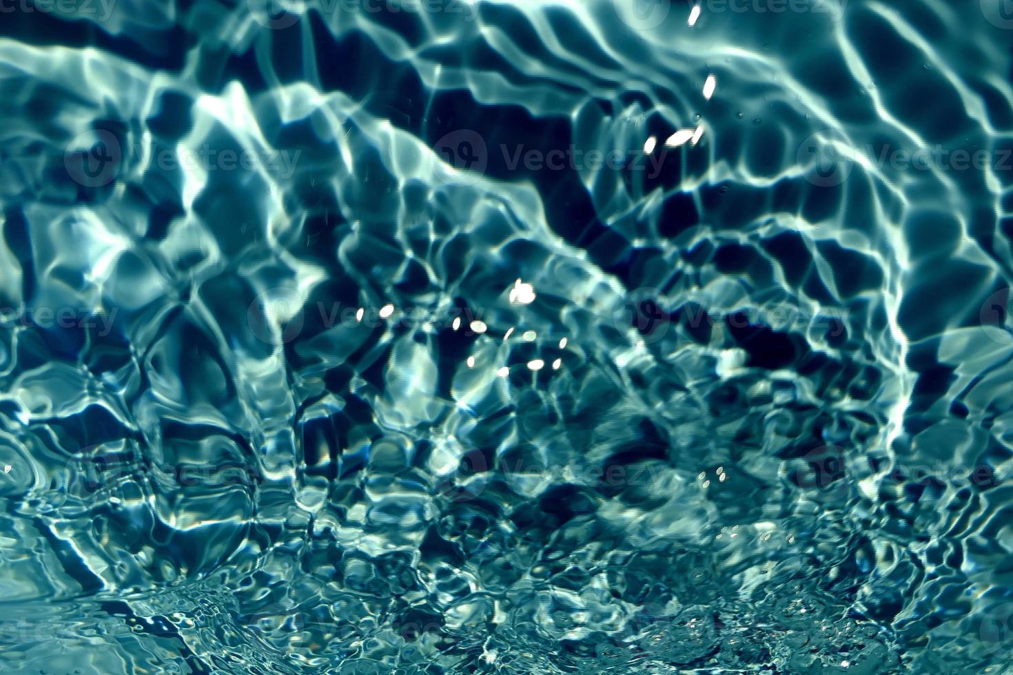 Defocus blurred transparent blue colored clear calm water surface texture with splashes and bubble. Trendy abstract nature background. Water wave in sunlight with copy space. Blue watercolor shining. photo