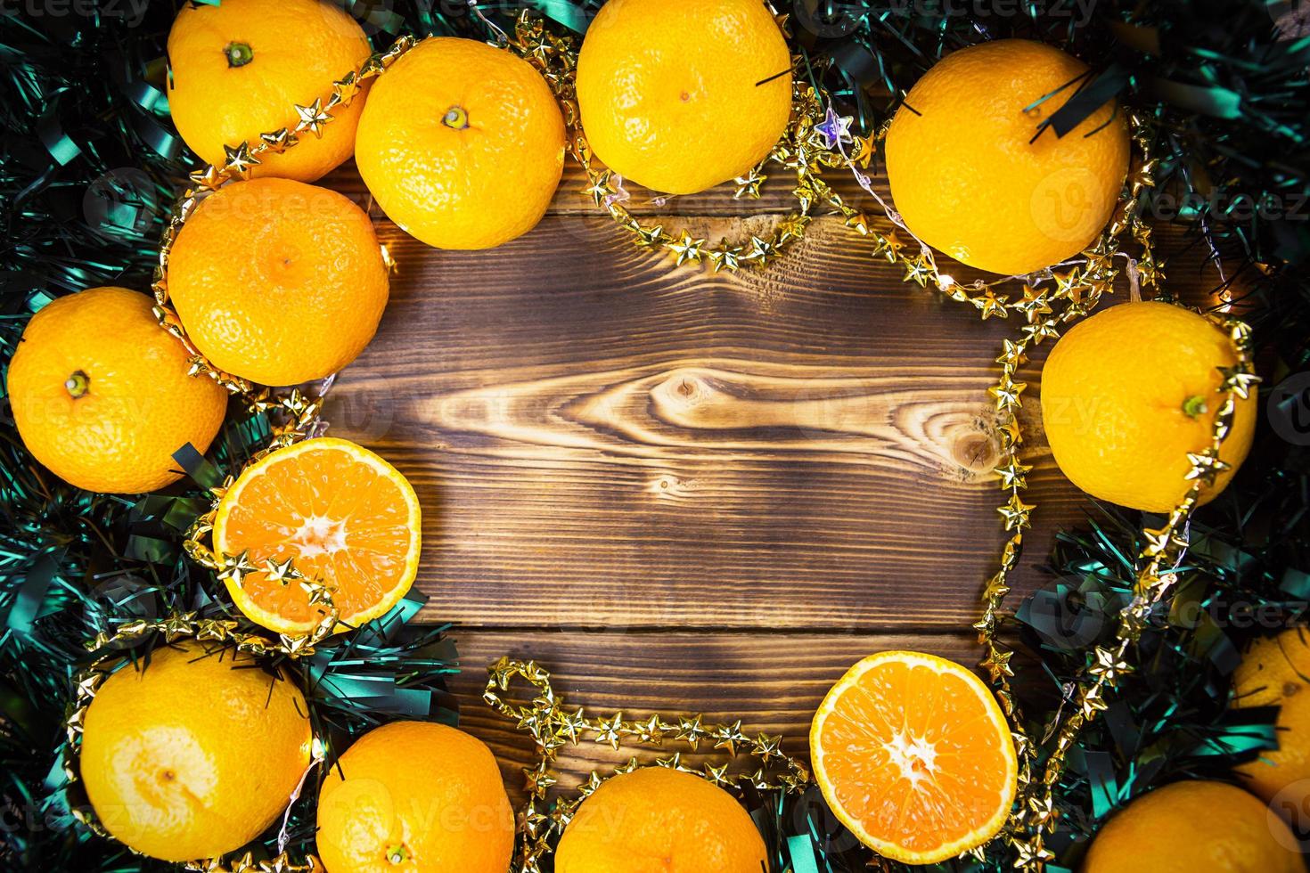 fondo de vacaciones de año nuevo hecho de madera con mandarinas, guirnaldas de luces y oropel verde. la mitad de una naranja, aroma cítrico de la fiesta. navidad, año nuevo. espacio para texto. cuadro foto