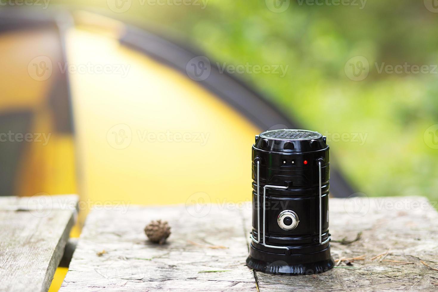 Camping portable lantern on a road pole with a tent in the background. The concept of hiking in nature, outdoor activities, equipment. photo