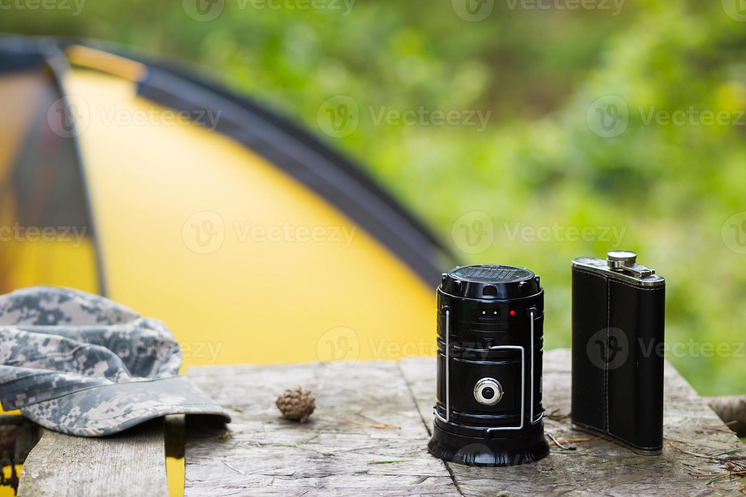 Camping portable lantern on a road pole with a tent in the background. The concept of hiking in nature, outdoor activities, equipment. photo