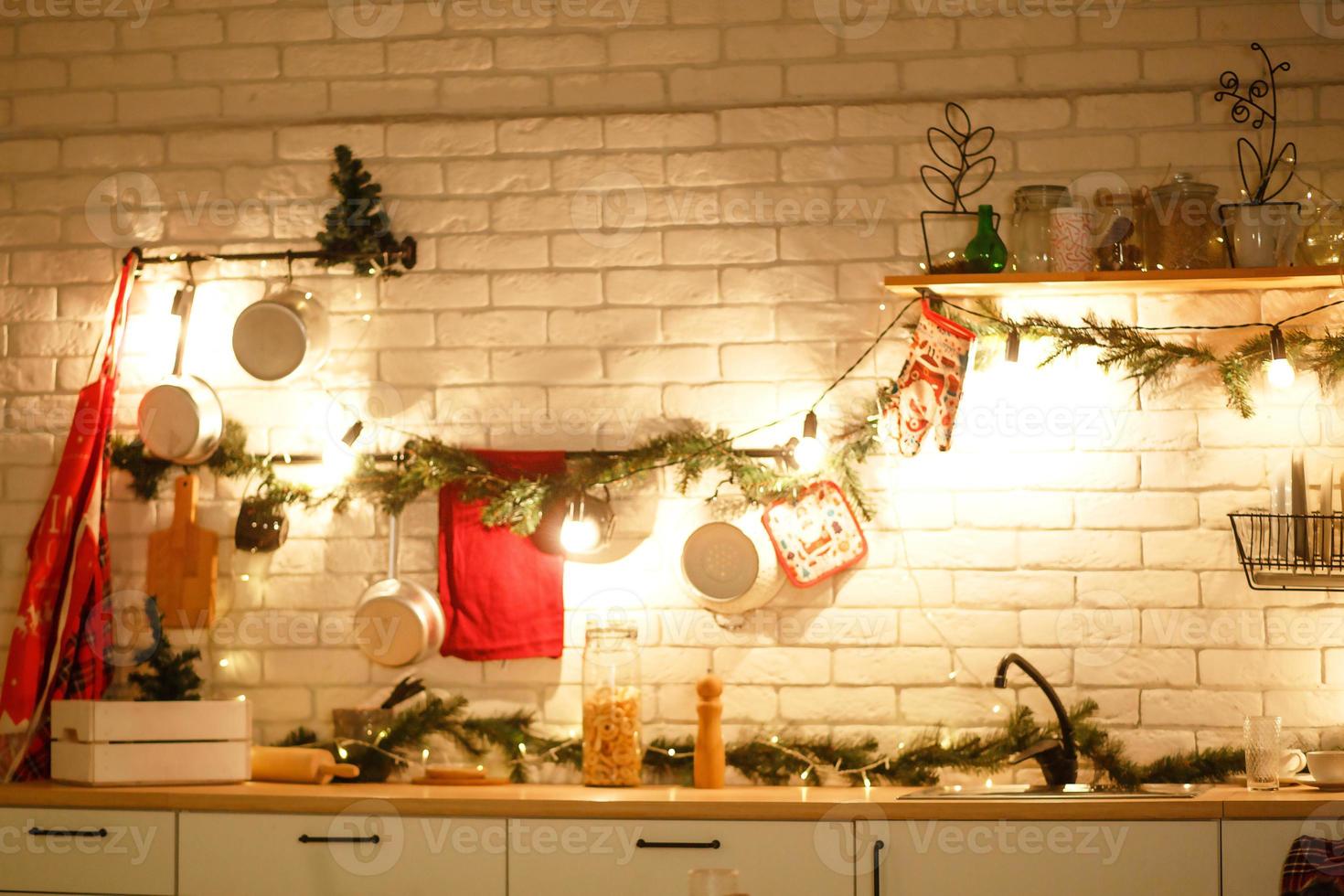 Christmas decor in the kitchen, preparing for the celebration. Lights of garlands, plates, incandescent lamps in loft style. Christmas tree, kitchen utensils. New year's eve, Christmas. House interior photo
