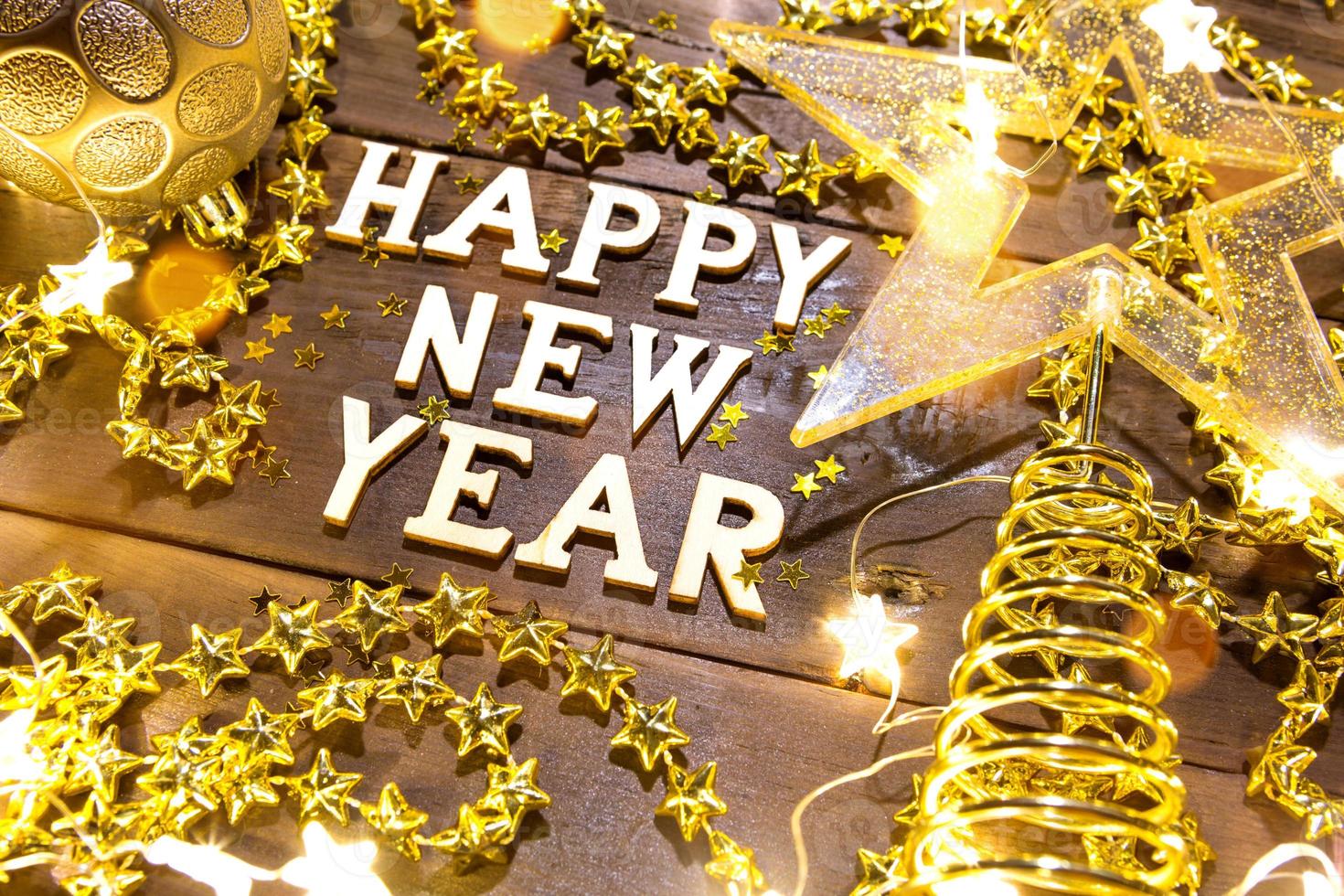 feliz año nuevo letras de madera sobre un fondo festivo con lentejuelas, estrellas, luces de guirnaldas. saludos, postal. foto